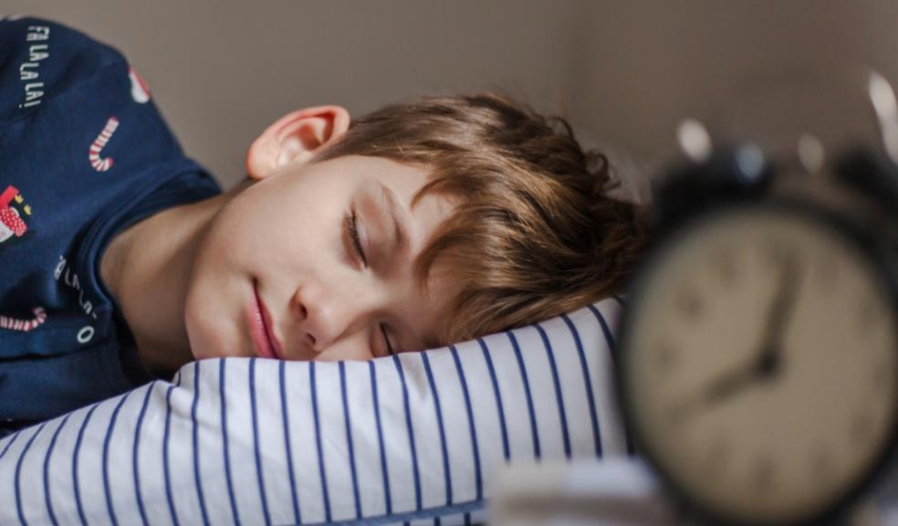 picture of a child asleep with an alarm clock on the bedside table