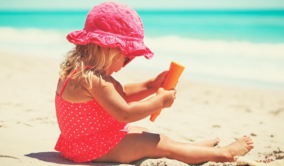 picture of child on a beach putting suncream on