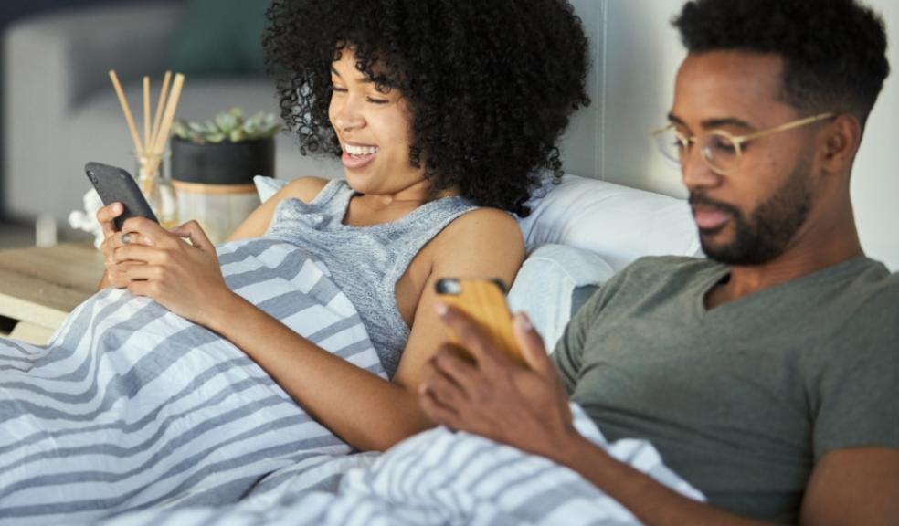 picture of a couple doing a quiz on their phones in bed
