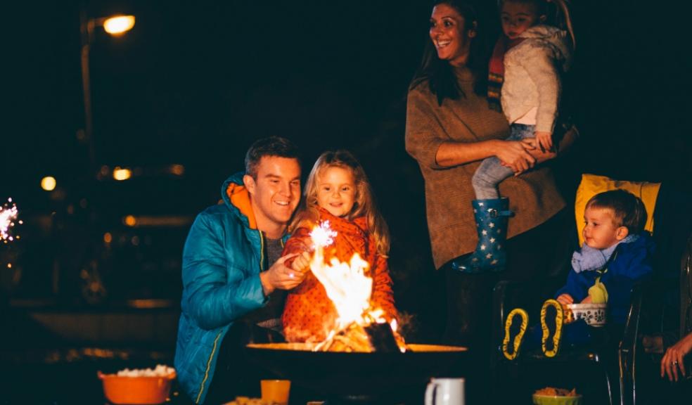 picture of a happy family sat around a fire pit with marshmallows