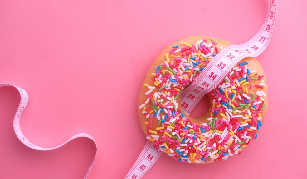 Picture of a donut with a measuring tape threading through