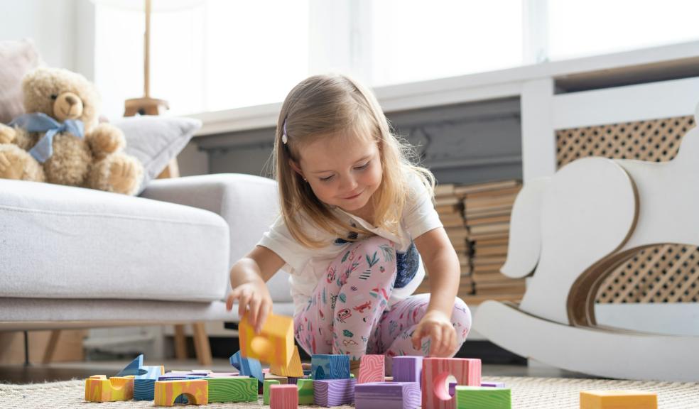 Little cute girl playing block toys in playroom at home