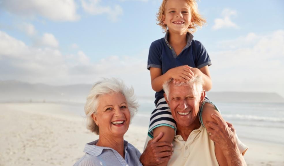 Picture of grandparents with their grandchild on their shoulders at the beach