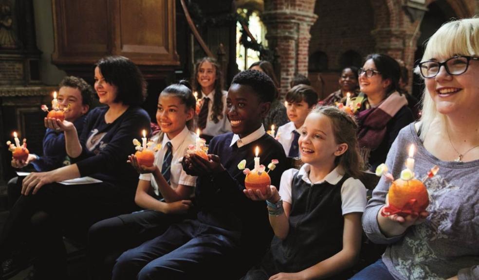 picture of children and adults sat in a church holding candles