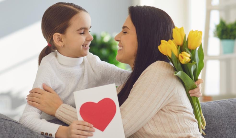 picture of a mum giving child a card and some flowers