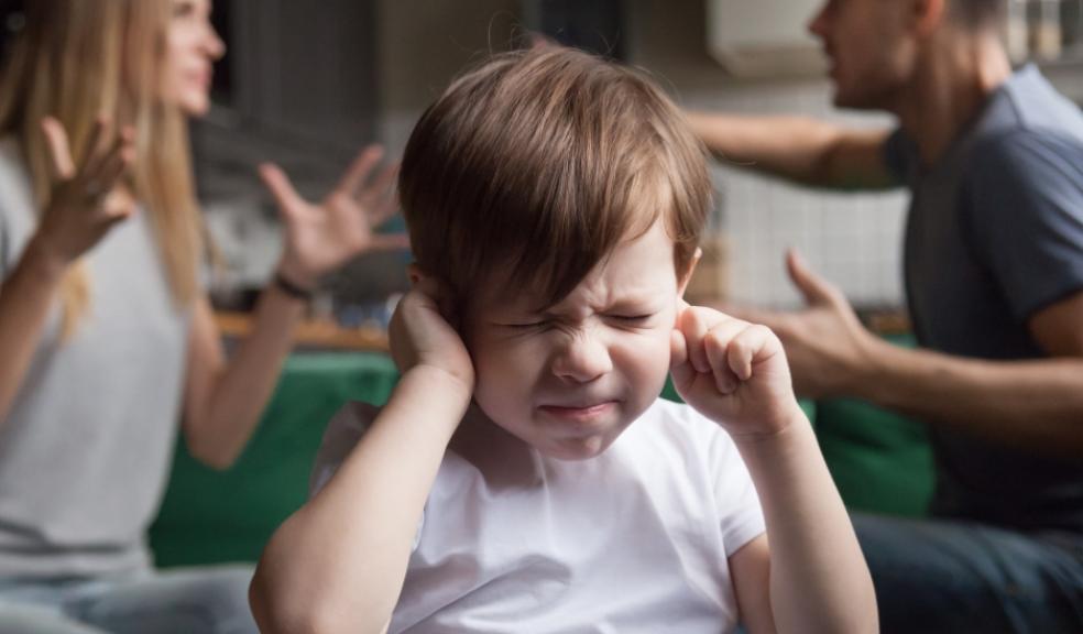 picture of parents arguing behind a child with his fingers in his ears