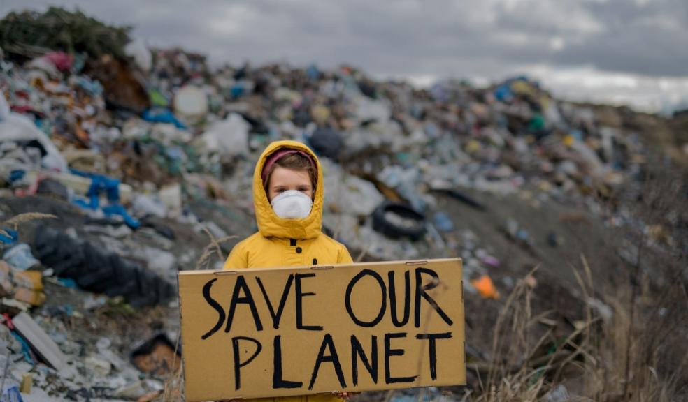 picture of a child at a rubbish dump holiday a sign saying save our planet