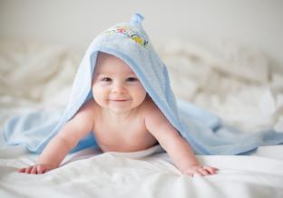 picture of a happy baby with a blue blanket on his head