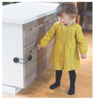 picture of a child at home with safety locks on kitchen cabinets