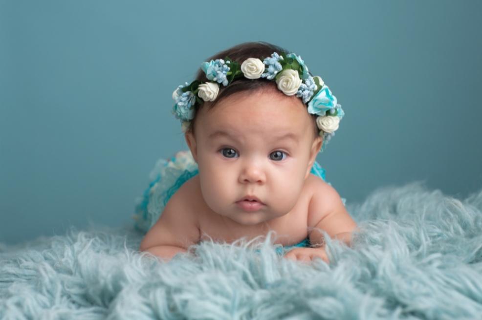 picture of a baby in blue with a floral headband