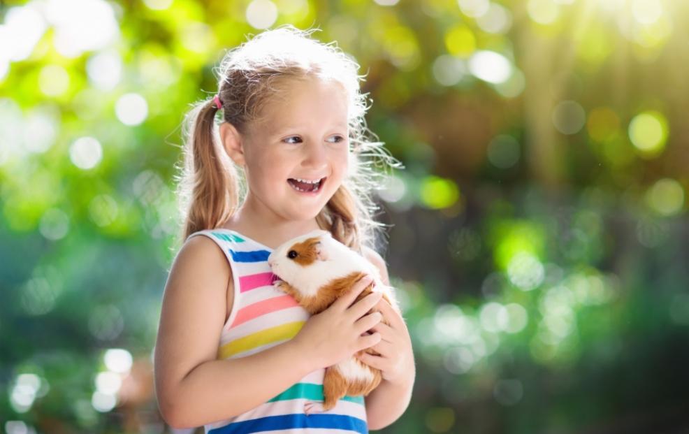 picture of a happy child holding a small pet outside
