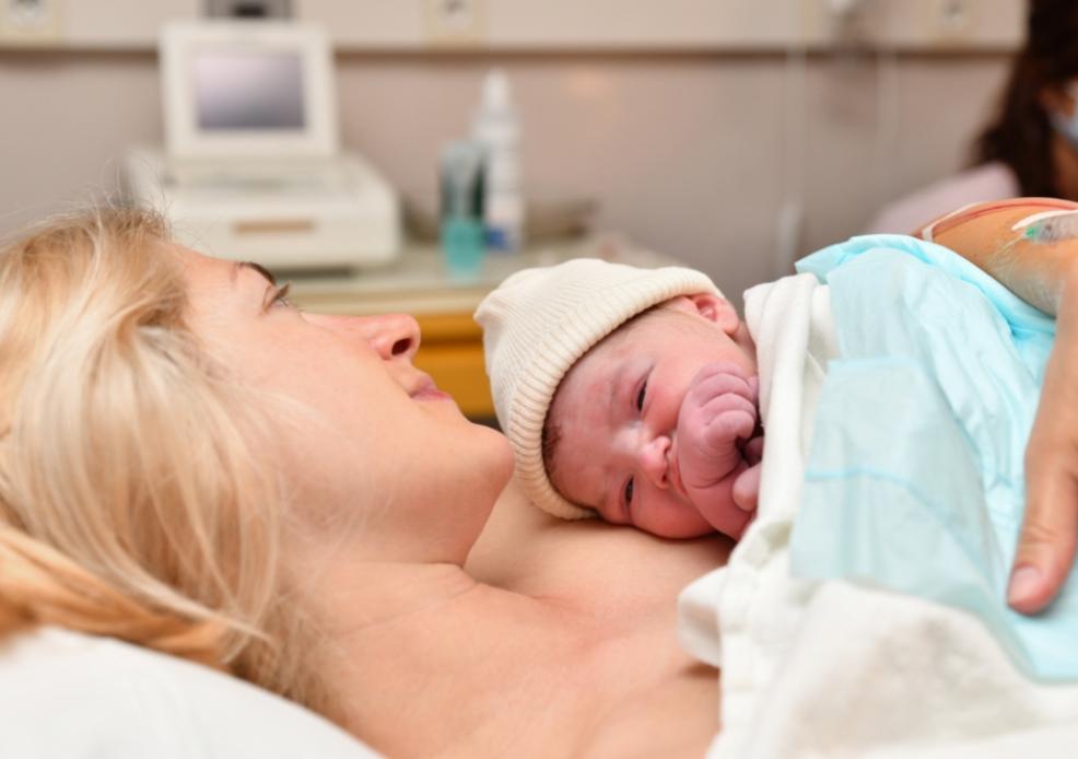 picture of mum and baby cuddling on a bed after childbirth