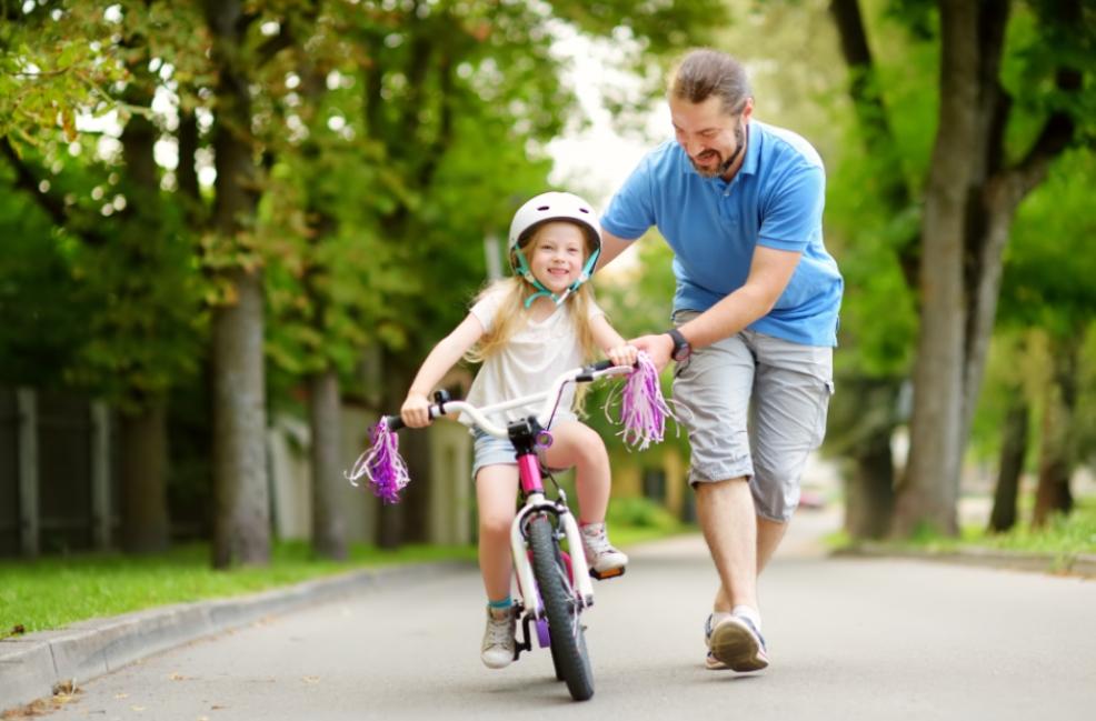 picture of a dad teaching his daughter to ride a bike