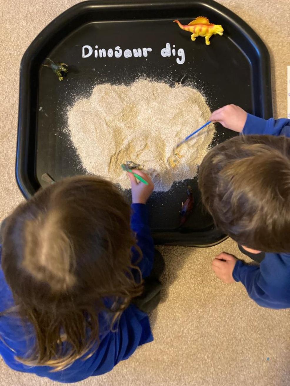 picture of children playing with a dinosaur tuff tray activity for kids