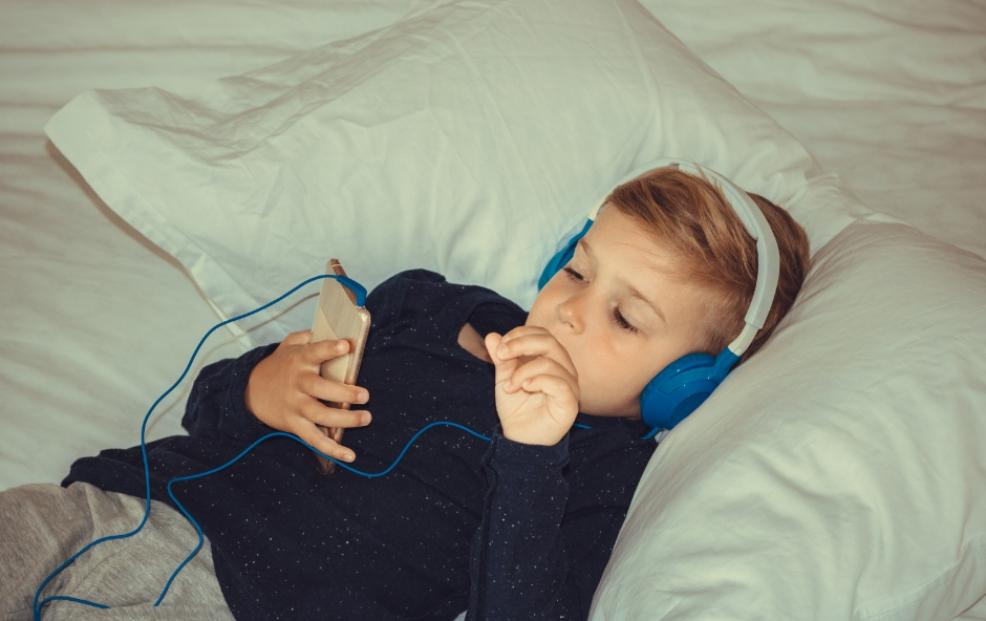 picture of boy watching device in bed