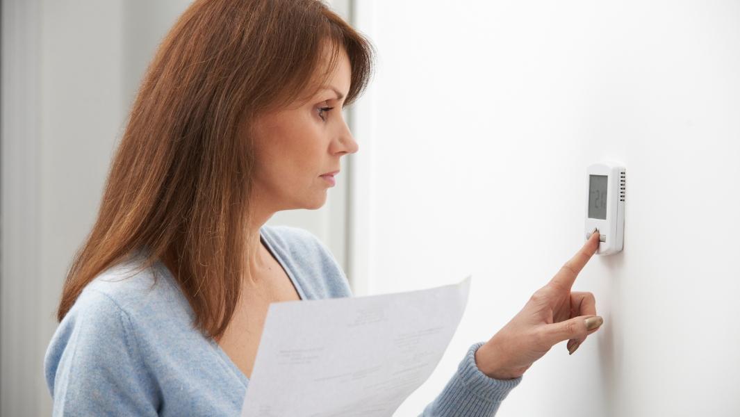 picture of woman turning the thermostat down picture of woman turning the thermostat down
