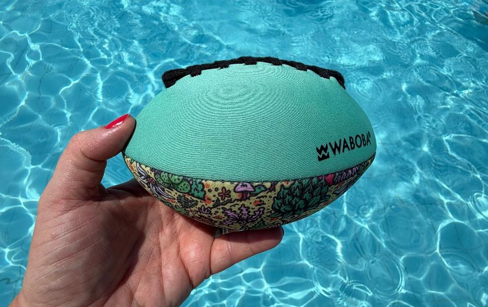 a woman holding the waboba rugby ball in a swimming pool picture of a woman holding the waboba rugby ball in a swimming pool