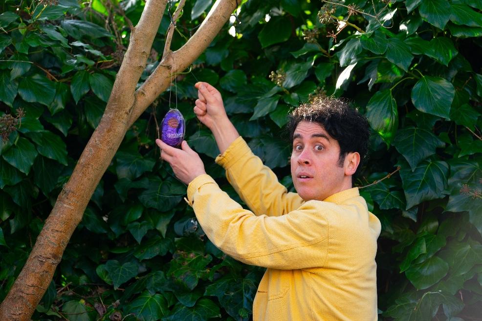 picture of magician Pete Firman hanging a cadbury easter egg from a tree for easter hunt