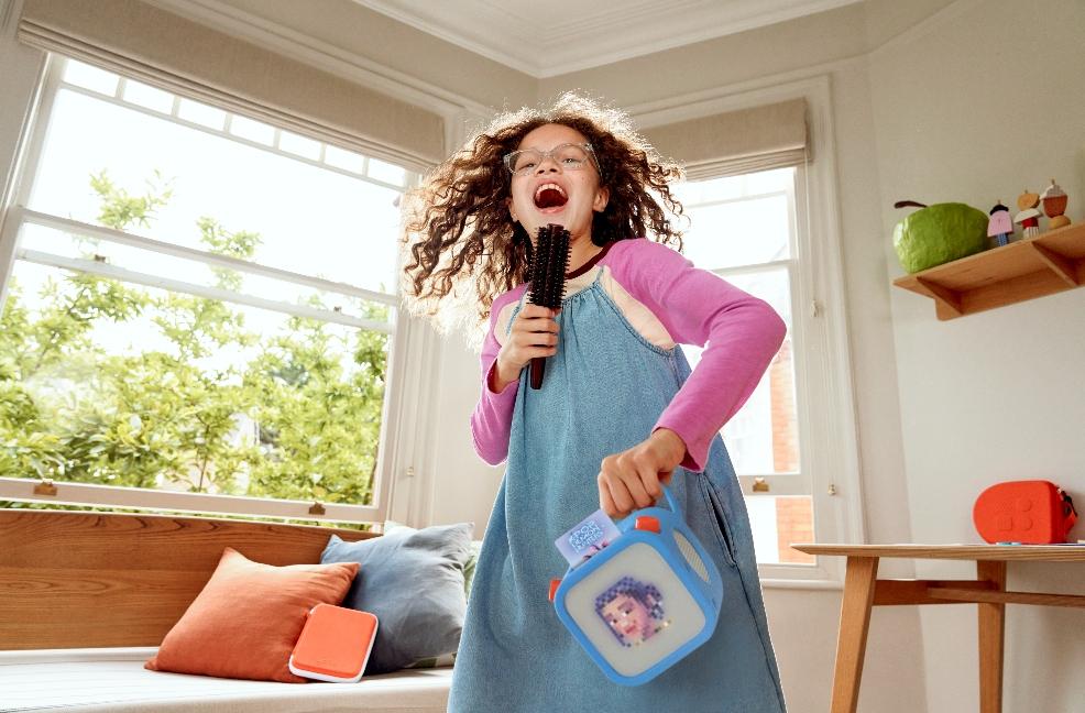picture of a happy child singing along to the KPop Demon Hunters on her Yoto player