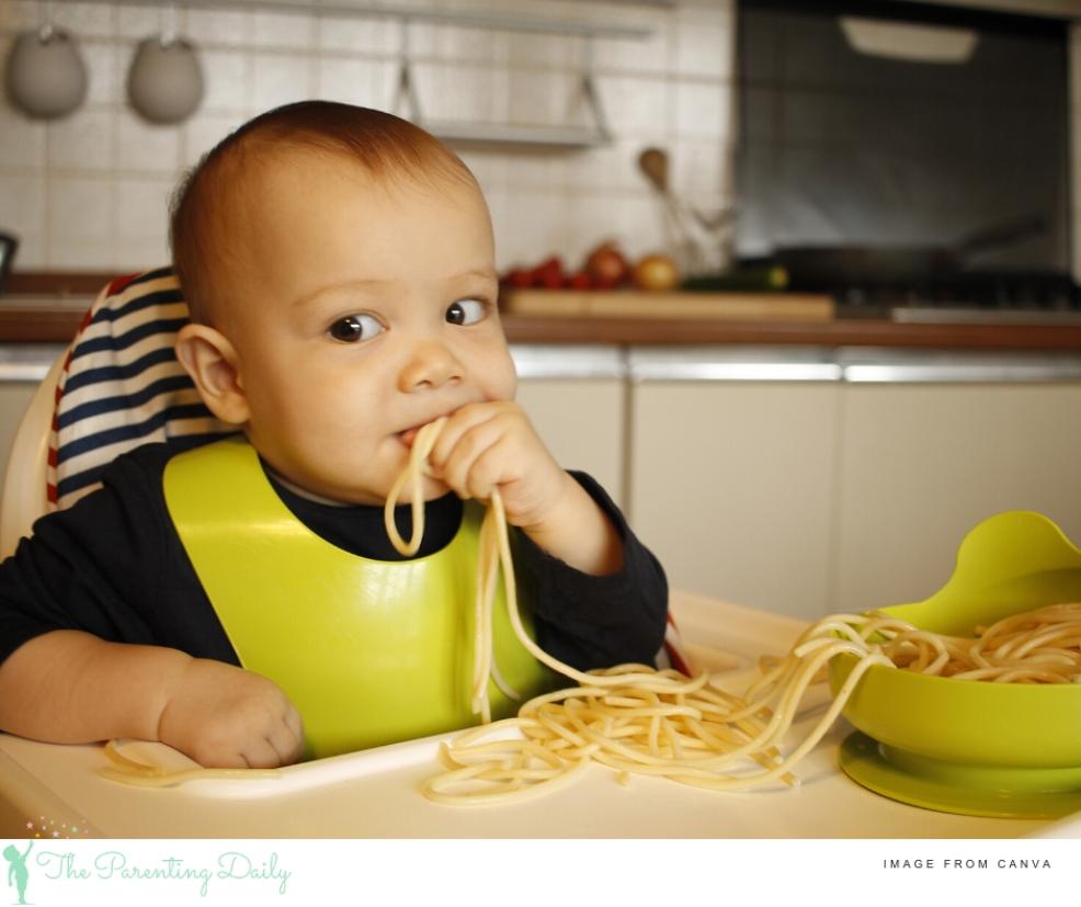 picture of a baby eating spaghetti as part of baby led weaning