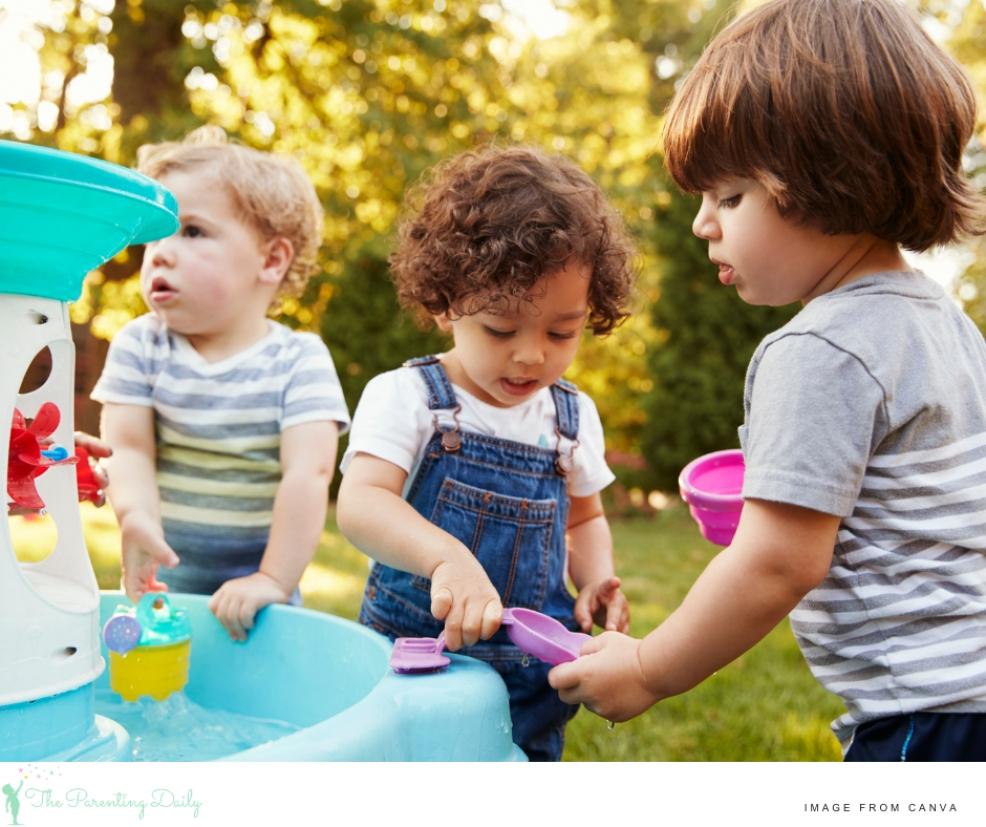 three toddlers having fun at a water play table for a summer activity picture of three toddlers having fun at a water play table for a summer activity