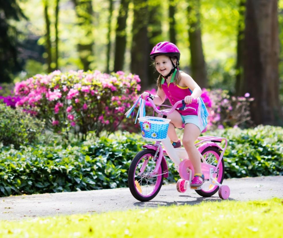picture of a child riding a pink bike with stabiliers