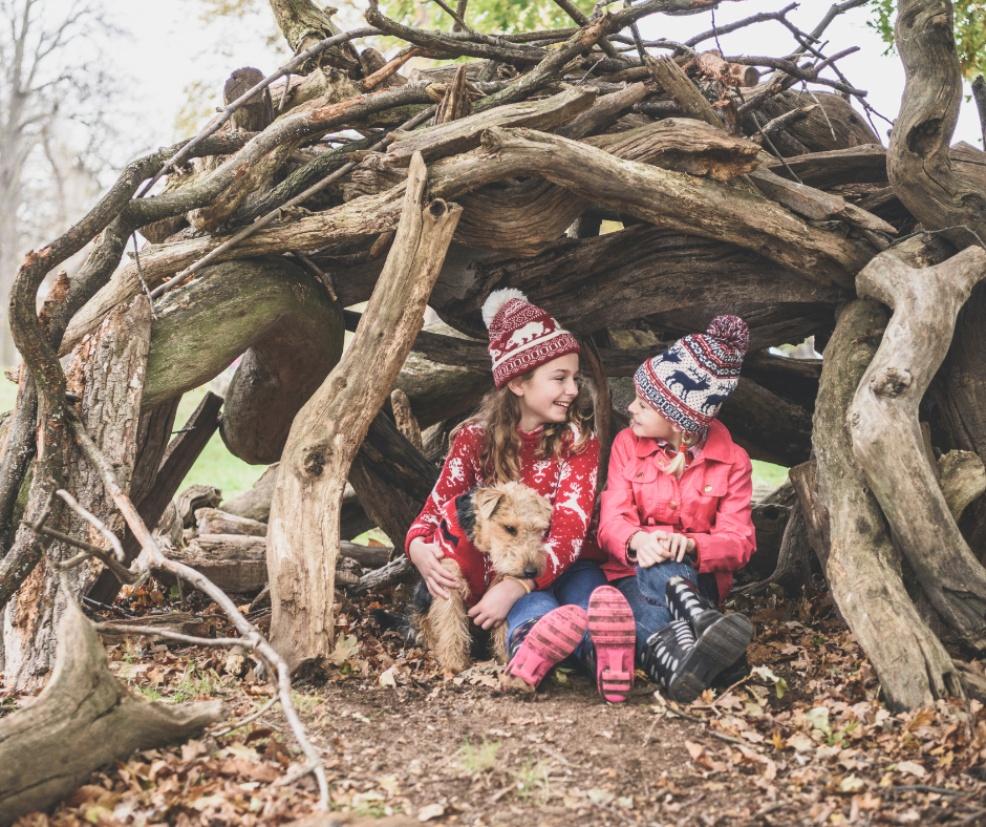 picture of children making an outdoor den with their dog
