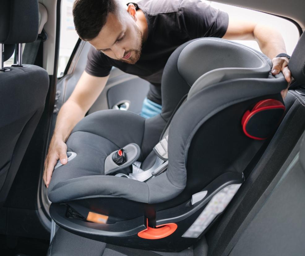 picture of a dad putting a car seat into a car