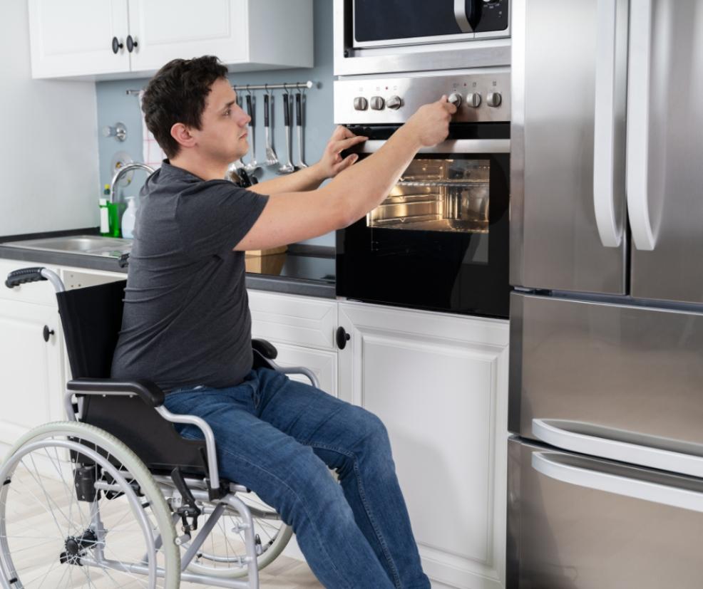 picture of a man in a wheelchair using an oven to cook
