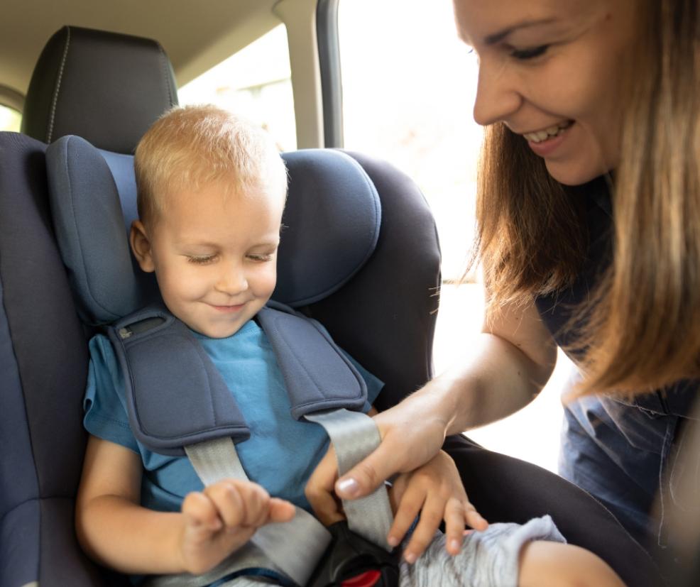 picture of a mum strapping child into a car seat