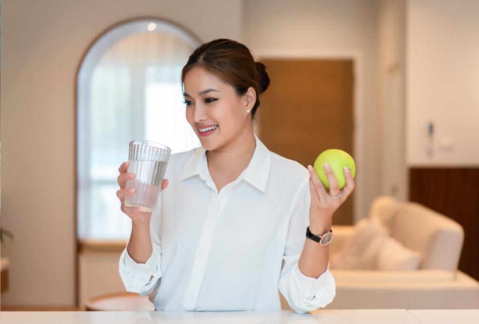 picture of a woman drinking water and eating an apple