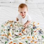 a happy baby sitting under an animal themed Loulou Lollipop blanket picture of a happy baby sitting under an animal themed Loulou Lollipop blanket