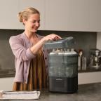 a mum in a kitchen using a Baby Brezza SuperQuick Steriliser Dryer picture of a mum in a kitchen using a Baby Brezza SuperQuick Steriliser Dryer