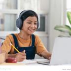 picture of a happy child wearing headphones and using a laptop for online learning