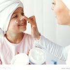 a happy child who suffers from dry skin having lotion put on her face picture of a happy child who suffers from dry skin having lotion put on her face