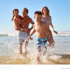 picture of a happy family running through the sea whilst on holiday