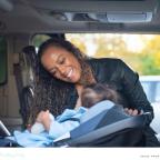 a happy mum putting her child into a rear facing carseat in the car to keep them safe picture of a happy mum putting her child into a rear facing carseat in the car to keep them safe