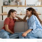 picture of a happy parent sat on a sofa talking to her teenage daughter