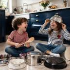picture of Two children playing music with pots and pans in a kitchen