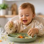 a happy baby sat in a high chair covered in food whilst they enjoy weaning picture of a happy baby sat in a high chair covered in food whilst they enjoy weaning