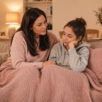 picture of a mum and daughter cuddled on the sofa under a blanket navigating changing hormones