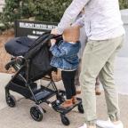 picture of parent using a lascal buggy board to walk toddler and baby to school