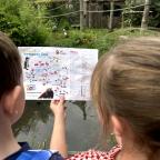 picture of children at Newquay Zoo holding a site map in front of a monkey enclosure