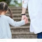 picture of a child holding hands and walking outside with her parent