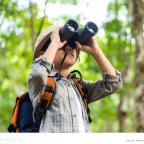 picture of a curious child in a forrest looking through binoculars