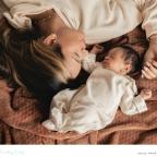 picture of a mum laying with her newborn baby on a brown blanket