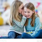 picture of two primary school children whispering to eachother while learning about friendship