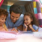 picture of a dad and daughters in a den reading