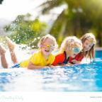 picture of happy children in brightly coloured swimwear by a pool