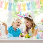 picture of happy children wearing bunny ears painting easter eggs